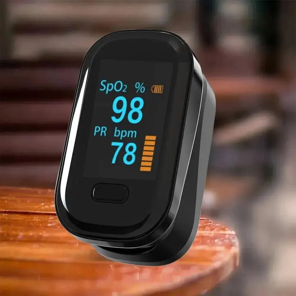 Portable fingertip pulse oximeter resting on table with clear OLED screen